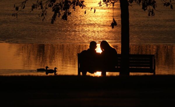 Couple walking on the Chicago Riverwalk at sunset with the skyline behind them
