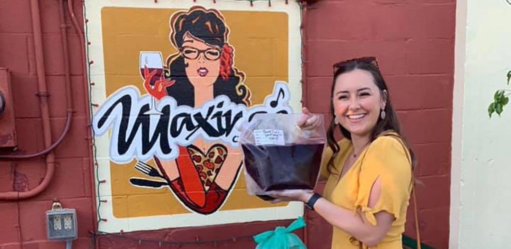 A pretty woman holding a bag of wine from Maxine's 