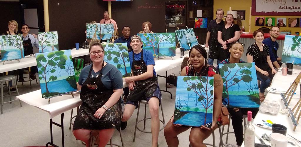 Ladies showing off their artwork at Painting with a Twist