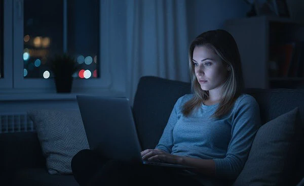 Woman using Flingster video chat on laptop late at night in cozy living room – best time to use Flingster