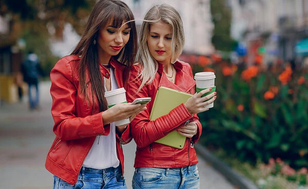 Persons using dating app on smartphone with urban city skyline in background