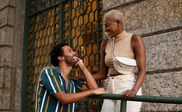 Diverse young couple enjoying a walk in a sunny urban setting with jacaranda trees, symbolizing modern dating connections via apps in a city like Pretoria, photorealistic image for dating blog header.